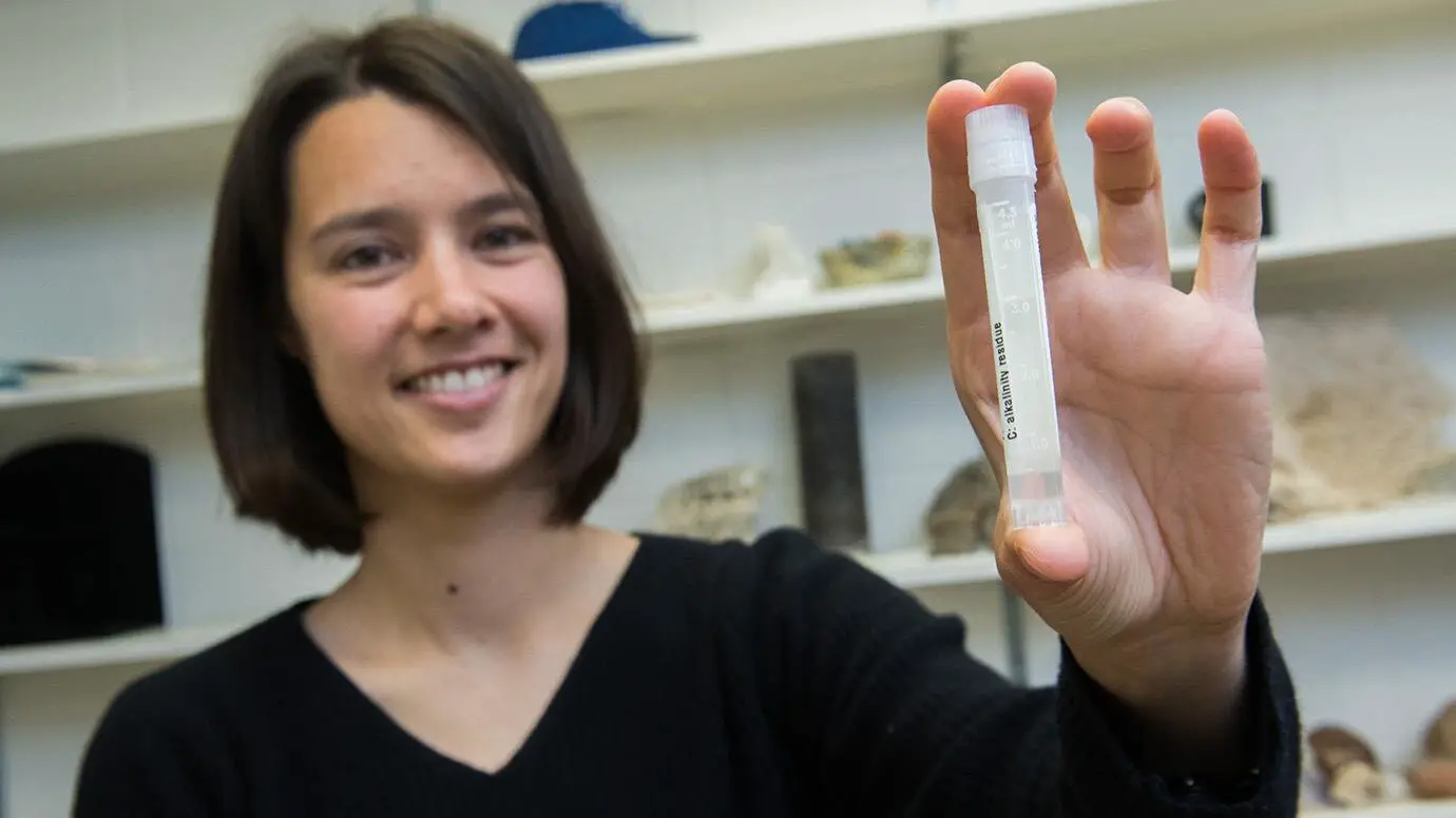 La professeure adjointe Clara Blättler avec une fiole d'eau de mer datant de la dernière période glaciaire, il y a environ 20 000 ans.
