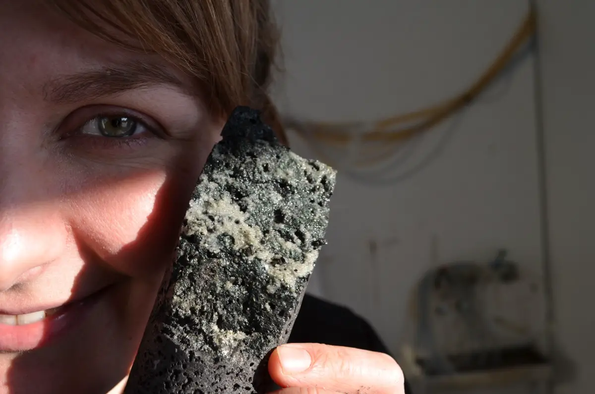 La co-auteure de l'étude, Sandra Snaebjornsdottir, détient un échantillon de roche volcanique chargée de carbonate solidifié, formé lorsque les chercheurs ont pompé du dioxyde de carbone dans la roche.