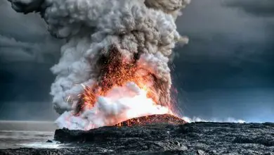 A volcano erupts in Hawaii near the water.