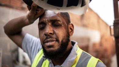 A male construction worker wipes sweat off his forehead.