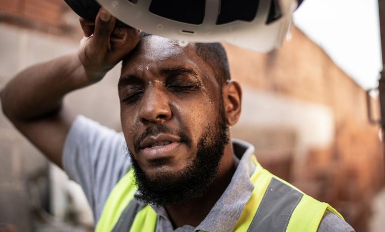 A male construction worker wipes sweat off his forehead.