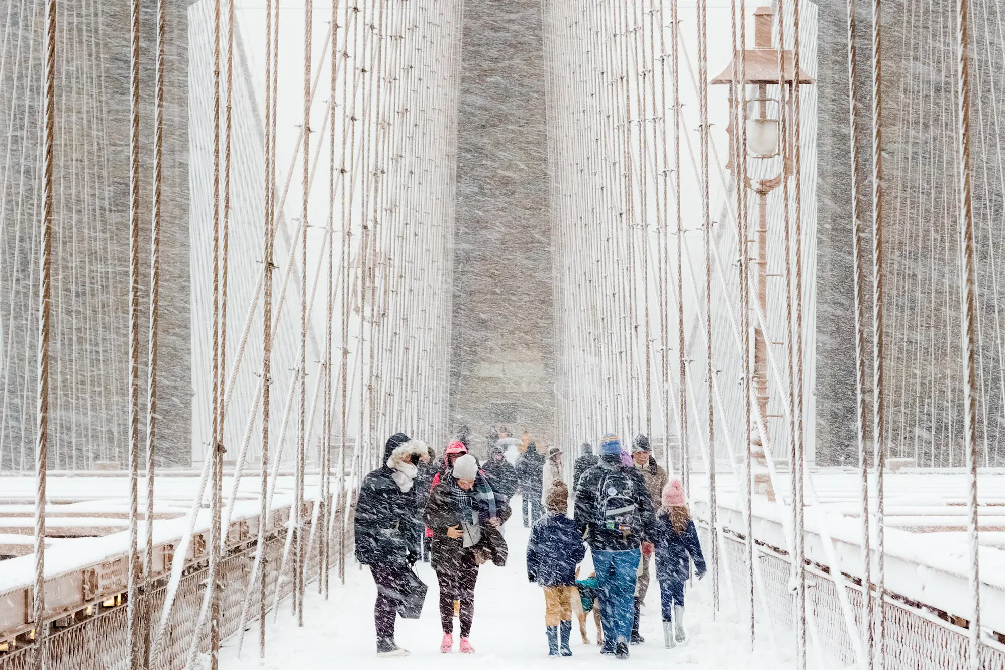 Les touristes frissonnent sur le pont de Brooklyn à New York lors d'un fort blizzard. Selon le photographe Rudolf Sulgan, le puissant blizzard a été amplifié par le changement climatique. 