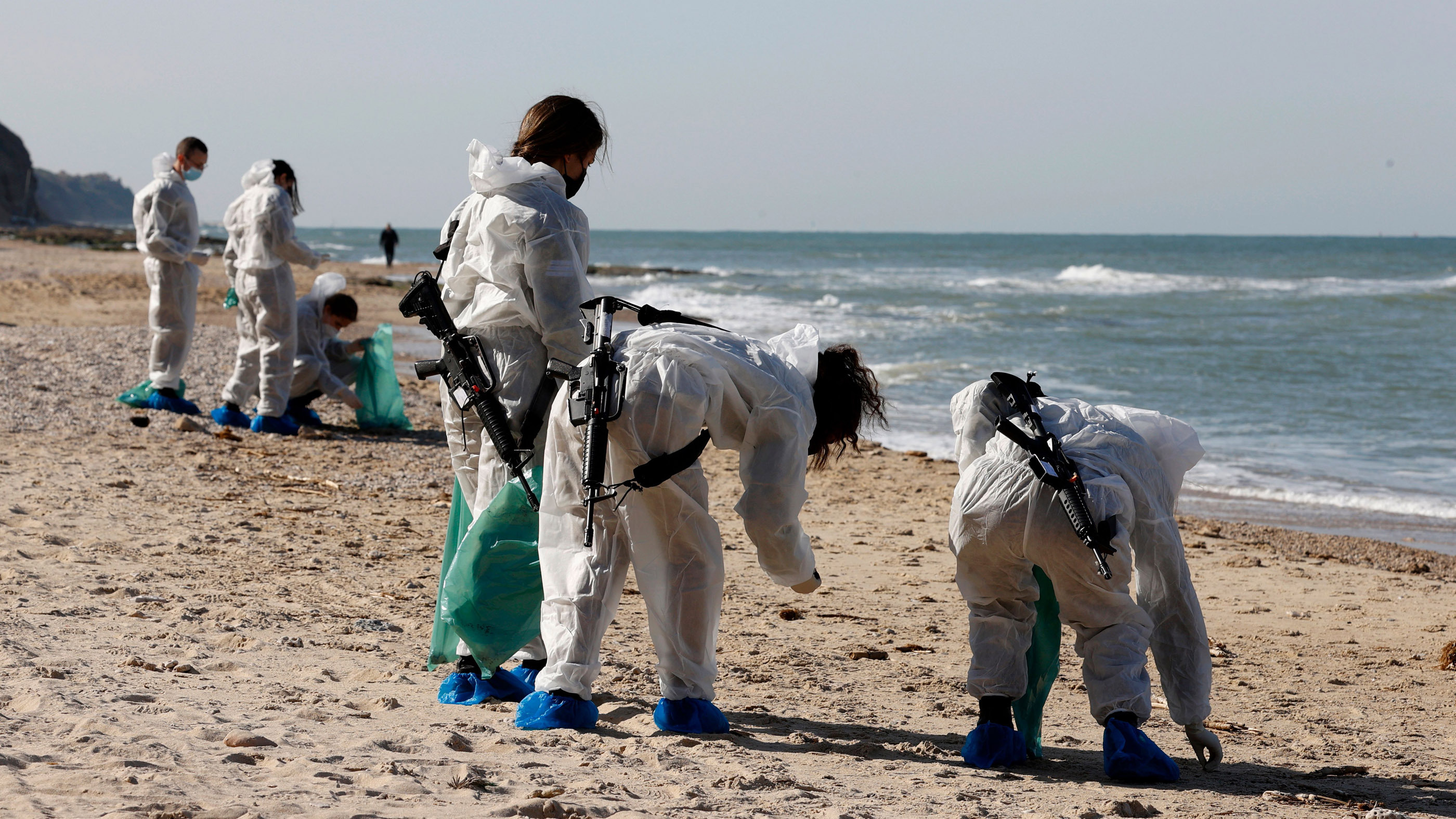 Des soldats israéliens enlèvent des boules de goudron lors d'une opération de nettoyage dans le parc national de la plage de Sharon, le 22 février.