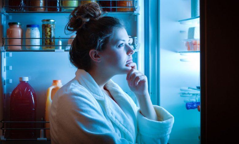 Woman looking in the fridge at night