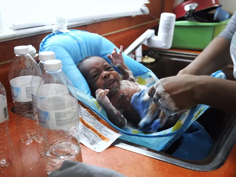 Une femme utilise de l'eau en bouteille pour laver son fils de trois semaines dans leur maison à Flint