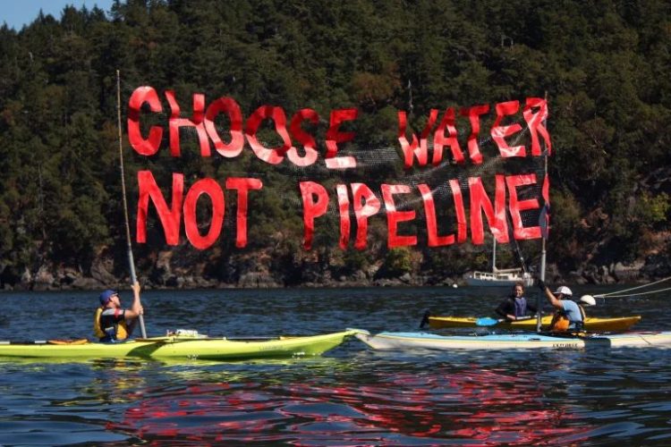Des "kayaktivistes" brandissent une banderole "Choisissez l'eau, pas les oléoducs" lors d'un "camp d'entraînement à la résistance aux oléoducs"