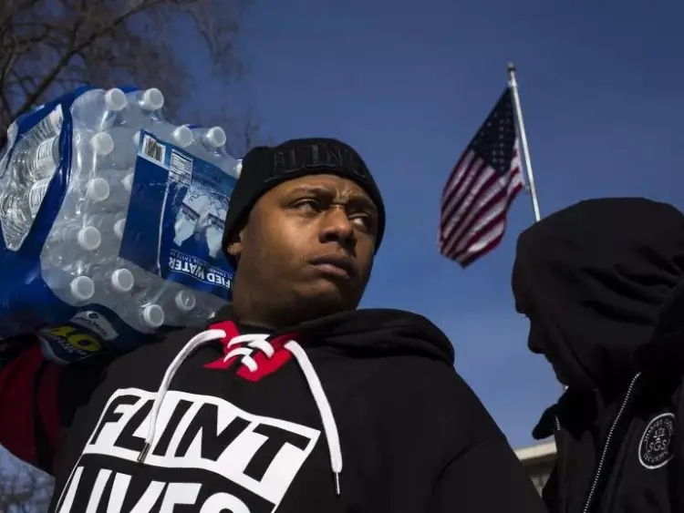 Le résident Lorenzo Lee Avery Jr. se tient devant l'hôtel de ville de Flint lors d'une manifestation "Flint Lives Matter" en 2016. La crise de l'eau qui sévit dans la ville a rendu les habitants dépendants de l'eau en bouteille.